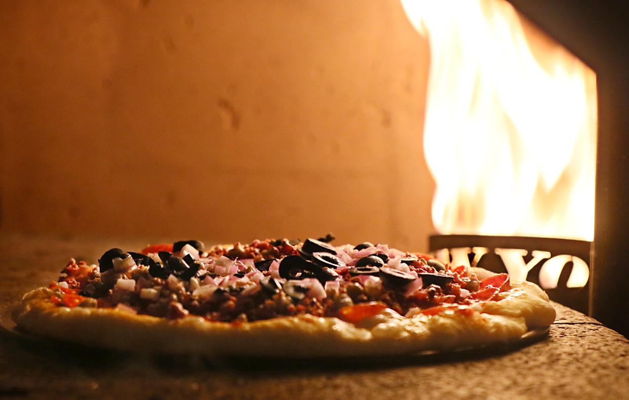 A Royal Feast pizza, made with pepperoni, sausage, bacon, onions, olives, basil and shaved parmesan, bakes in the brick oven in the kitchen of Kittle's Brick Oven Pub in Green.