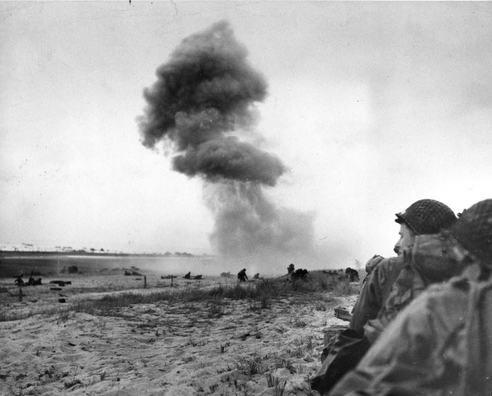 FILE - Under heavy bombardment by German 88mm guns, American soldiers flatten themselves on the sand as they move up the shore, during Allied landing operations in Normandy, France, June 12, 1944. The D-Day invasion that helped change the course of World War II was unprecedented in scale and audacity. Veterans and world dignitaries are commemorating the 79th anniversary of the operation. (AP Photo, File)