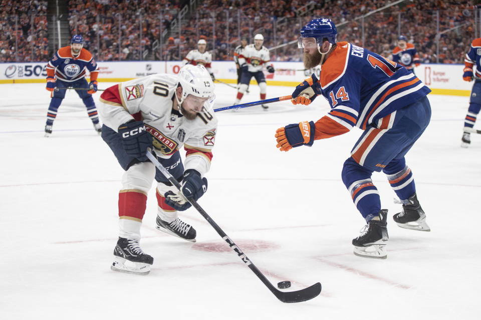 Florida Panthers' Vladimir Tarasenko (10) reaches for the puck as Edmonton Oilers' Mattias Ekholm (14) defends during the first period of Game 4 of the NHL hockey Stanley Cup Final, Saturday, June 15, 2024, in Edmonton, Alberta. (Jason Franson/The Canadian Press via AP)