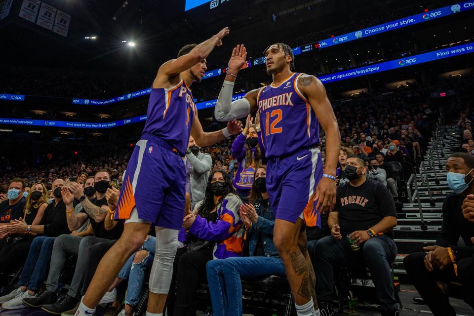 After running off the court, Phoenix Suns forward Ish Wainright returns to the court and high fives guard Devin Booker (1) at the Footprint Center on Monday, Jan. 24, 2022.