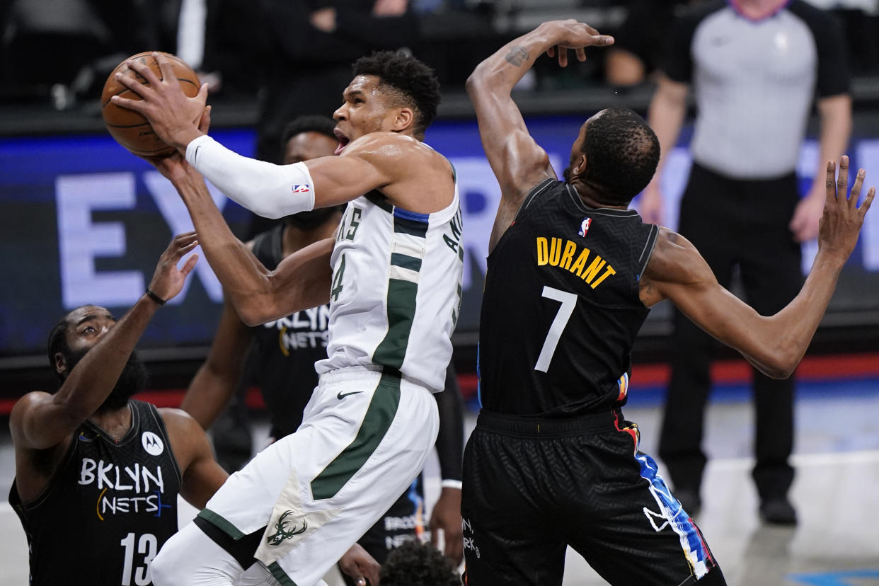 Brooklyn Nets guard James Harden (13) and Brooklyn Nets forward Kevin Durant (7) try to contain Milwaukee Bucks forward Giannis Antetokounmpo (34) in Game 5 of a second-round NBA basketball playoff series, Tuesday, June 15, 2021, in New York. (AP Photo/Kathy Willens)