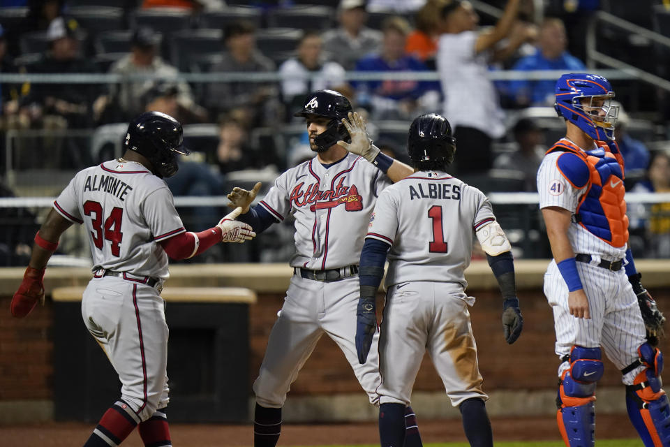 Atlanta Braves' Dansby Swanson celebrates with teammates Abraham Almonte (34) and Ozzie Albies (1) after hitting a three-run home run as New York Mets catcher James McCann looks away during the third inning of a baseball game Tuesday, June 22, 2021, in New York. (AP Photo/Frank Franklin II)