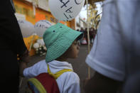 A child, student of the Enrique C. Rebsamen primary school, walks in the funeral procession of 7-year-old murder victim Fatima, accompanied by his parents in Mexico City, Tuesday, Feb. 18, 2020. Fatima was abducted from the door of the primary school and her body was found wrapped in a bag and abandoned in a rural area on Saturday. Five people have been questioned in the case and video footage of her abduction exists. (AP Photo/Marco Ugarte)