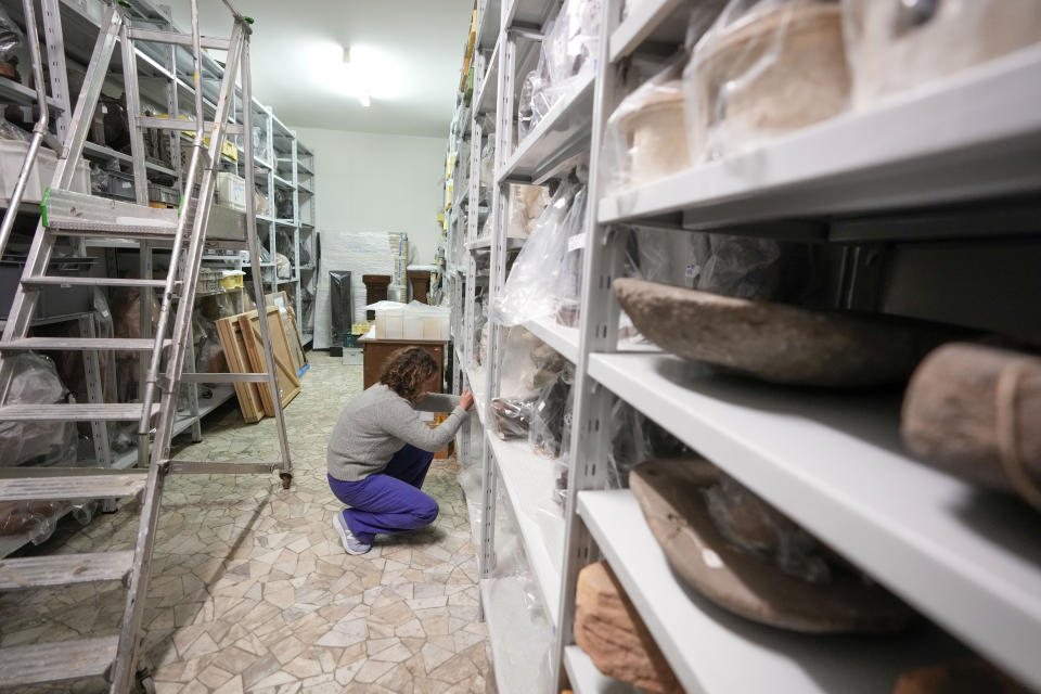 Anthropologist Gaia Delpino looks at artifacts from to the Italian colonialist period in a deposit of the Museo delle Civilta', Museum of Civilizations, in Rome, Friday, April 14, 2023. Italy, a long time victim of antiquities theft that has worked for decades to recover its treasures, is coming to terms with the fact that it, too has stolen loot in its museum collections: the relics of a brutal colonial empire that the country hasn't fully reckoned with. (AP Photo/Andrew Medichini)