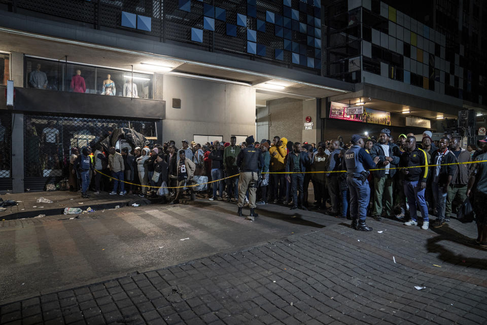 Onlookers gather at the scene of a gas explosion downtown Johannesburg, South Africa, Wednesday July 19, 2023. Search and rescue officials also ordered residents in nearby buildings to evacuate the area and the area where the explosion happened was cordoned off. (AP Photo/ Shiraaz Mohamed)