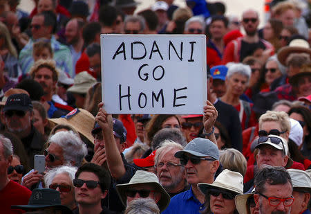 A protester holds a sign as he participates in a national Day of Action against the Indian mining company Adani's planned coal mine project in north-east Australia, at Sydney's Bondi Beach in Australia, October 7, 2017. REUTERS/David Gray