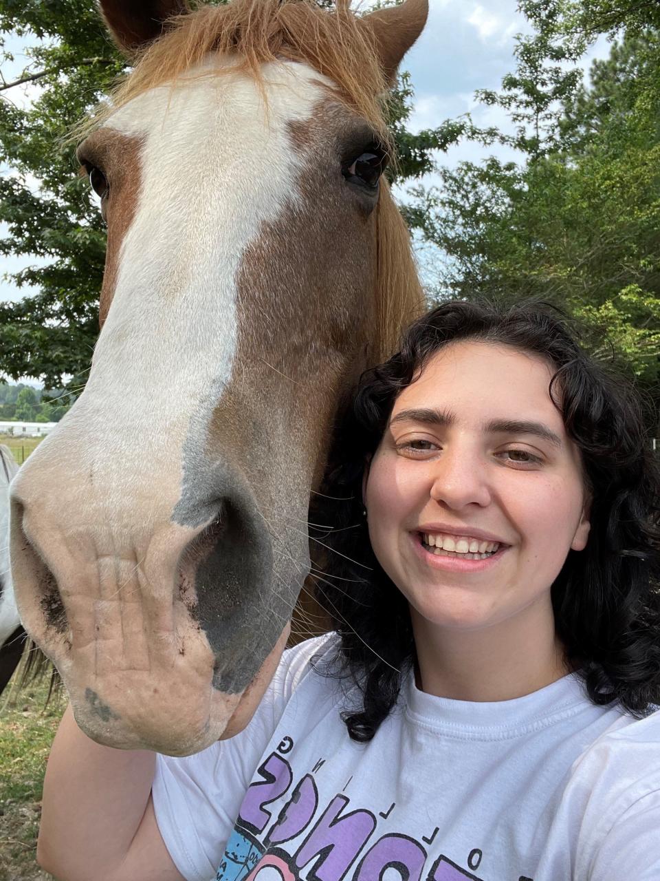 Living Democracy student Payton Davis smiles beside a horse in her summer community of Collinsville.