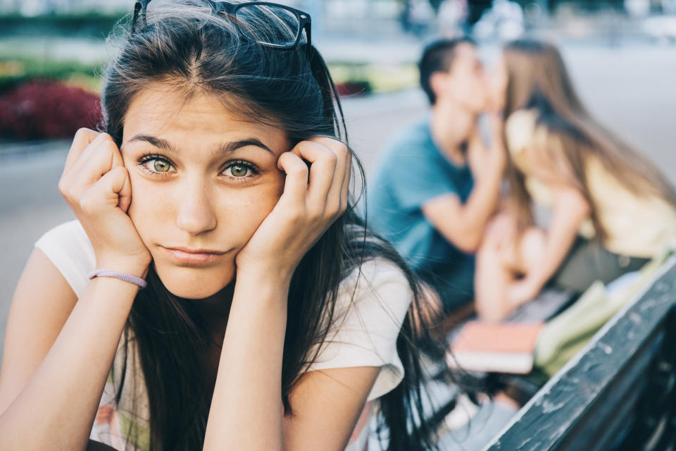 Close-up of woman sitting with her head in her hands with a couple behind her