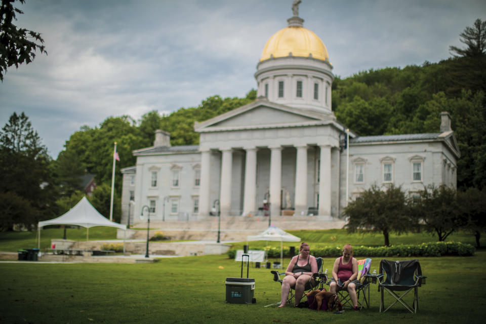 Montpelier residents sunbathe by the Capitol building beside State street which was one one of the most damaged parts of the state's capital in result of 2023 flood, July 3 2024. A year after catastrophic flooding inundated parts of Vermont, some homeowners are still in the throes of recovery. (AP Photo/ Dmitry Belyakov)