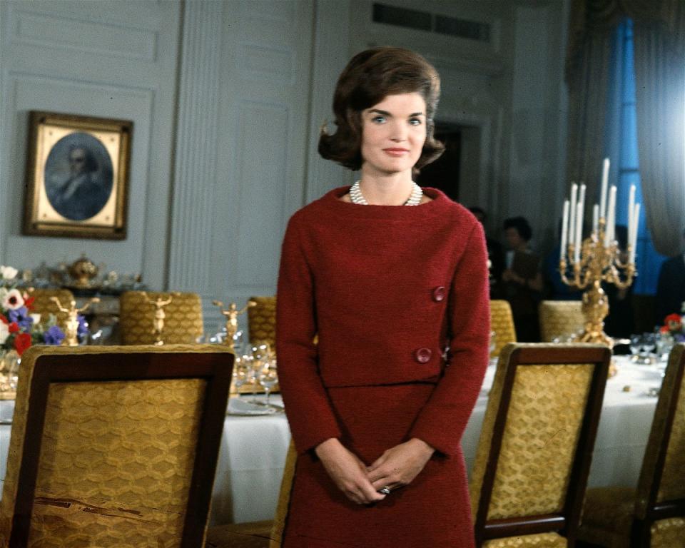 <p>First Lady Jackie Kennedy stands before a dining room table in the White House during the filming of the now-iconic CBS News Special program "'A Tour of the White House with Mrs. John F. Kennedy". The program saw Jackie taking CBS News correspondent Charles Collingwood on a tour of the White House and showing off its brand new restoration, a project which she had personally overseen. </p>