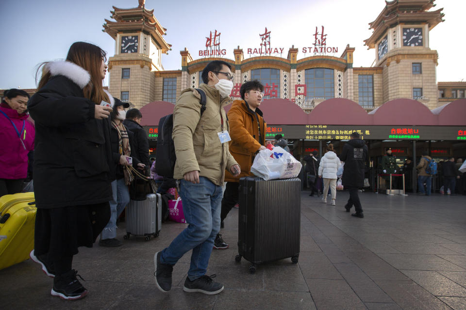 A traveler wears a face mask as he walks outside of the Beijing Railway Station in Beijing, Monday, Jan. 20, 2020. China reported Monday a sharp rise in the number of people infected with a new coronavirus, including the first cases in the capital. The outbreak coincides with the country's busiest travel period, as millions board trains and planes for the Lunar New Year holidays. (AP Photo/Mark Schiefelbein)