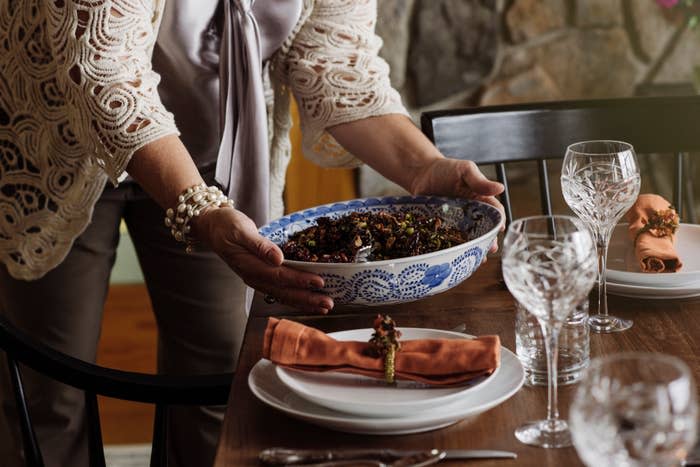 A woman is bringing food out to the dining table