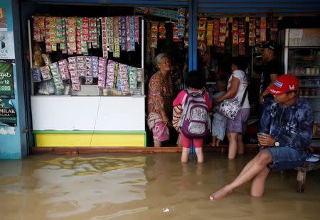 A shop keeper chats with customers after heavy seasonal rains caused the Citarum river to flood in Dayeuhkolot, south of Bandung, West Java province, Indonesia, February 23, 2018. REUTERS/Darren Whiteside