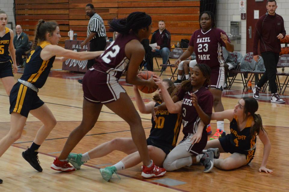 Airport and Hazel Park girls basketball players wrestle for a loose ball Friday, February 24, 2023.