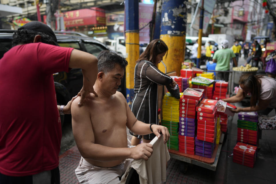 A man massages a costumer along a street at Binondo district, said to be the oldest Chinatown in the world, in Manila, Philippines on Monday, Feb. 5, 2024. Crowds are flocking to Manila's Chinatown to usher in the Year of the Wood Dragon and experience lively traditional dances on lantern-lit streets with food, lucky charms and prayers for good fortune. (AP Photo/Aaron Favila)