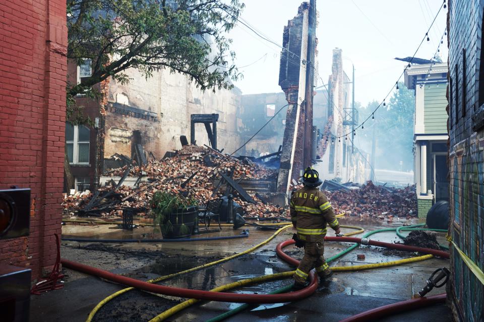 A Linden firefighter walks near the rubble of the Battle Alley Arcade Antiques Mall after it caught fire on Tuesday, June 21, 2022 in Holly.