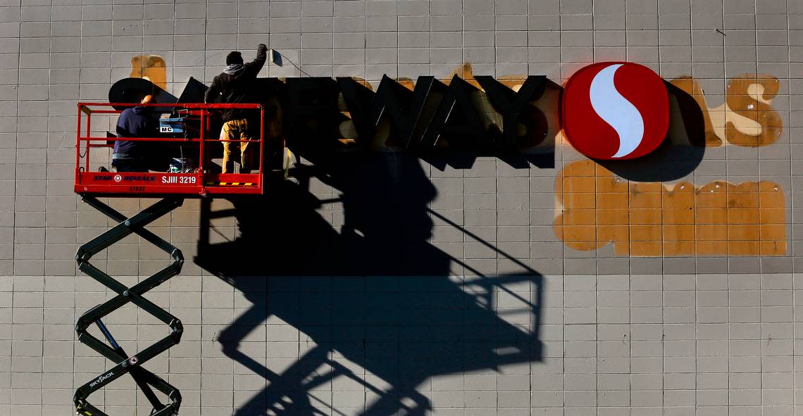Workers on a scissor lift carefully paint around a new Safeway sign to cover the outlines of lettering at the former Albertsons grocery store on West Clearwater Avenue in Kennewick.