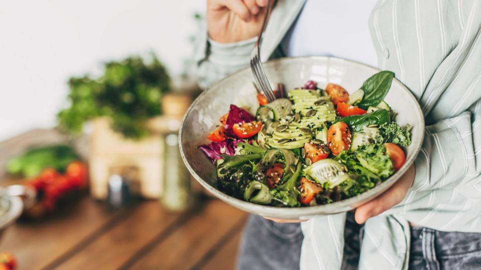 Woman holding a bowl of salad with foods suitable for low-fat diet