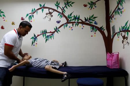 Miguel Antón ayuda a su hijo José Gregorio Antón de 11 años, tras un examen de sangre. El niño tiene una enfermedad neurológica y es tratado con anticonvulsivos. La Guaira, Venezuela. REUTERS/Carlos Garcia Rawlins. 20 de febrero de 2017