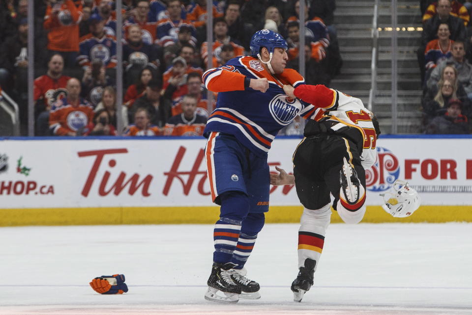 Calgary Flames' Anthony Peluso (16) and Edmonton Oilers' Milan Lucic (27) fight during first period NHL hockey action in Edmonton, Alberta on Sunday, Dec. 9, 2018. (Jason Franson/The Canadian Press via AP)