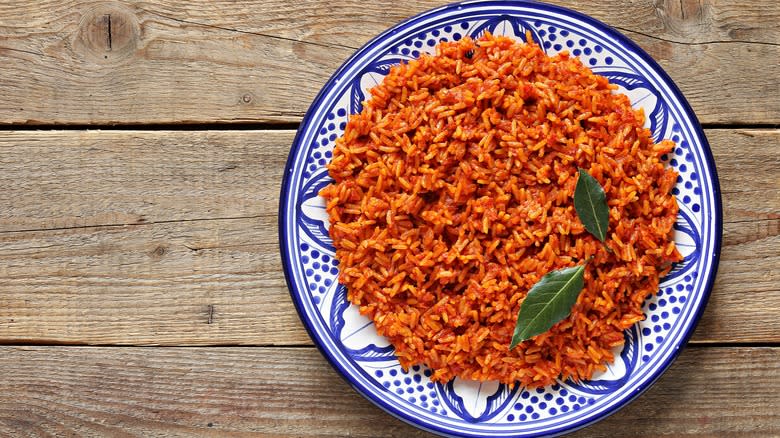 jollof rice in a blue and white patterned bowl over a wood surface