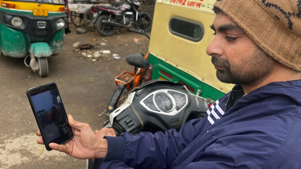 Mohammad Aman, a 32-year-old Salon worker from Delhi, looks at photos of the mosque demolition on his phone. - Aishwarya Iyer/CNN