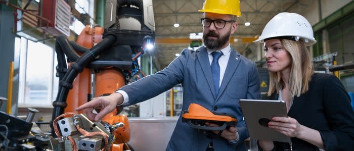 Two technicians interact with an industrial robot.