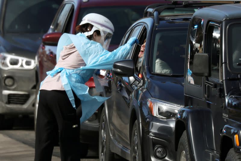 Health care worker tests people at a drive-thru testing station run by the state health department, for people who suspect they have novel coronavirus, in Denver