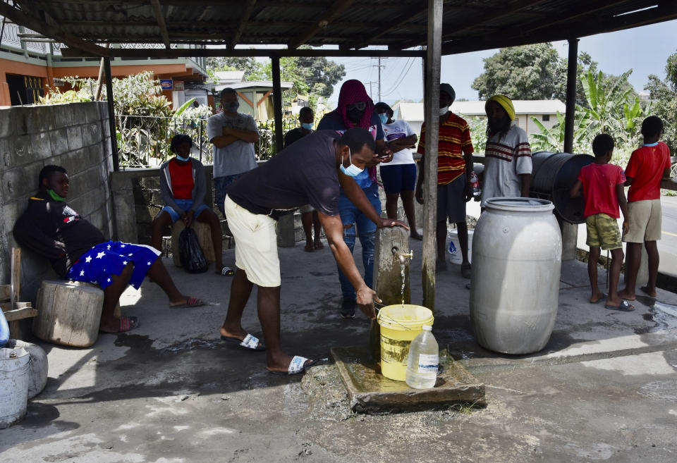 People collect water not contaminated by volcanic ash after the eruption of La Soufriere volcano in Wallilabou, on the western side of the Caribbean island of St. Vincent, Monday, April 12, 2021. (AP Photo/Orvil Samuel)