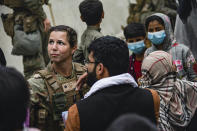 In this image provided by the U.S. Marines, a U.S. Airman with the Joint Task Force-Crisis Response speaks with families who await processing during an evacuation at Hamid Karzai International Airport in Kabul, Afghanistan, Friday, Aug. 20, 2021. (Cpl. Davis Harris/U.S. Marine Corps via AP)