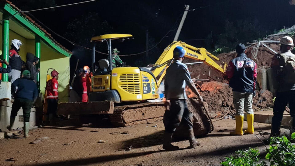 In this photo provided by the Indonesian National Disaster Mitigation Agency, rescuers work the scene of a landslide in Cihanjuang village, Indonesia, early Sunday, Jan. 10, 2021. Two landslides in the Sumedang district of West Java province triggered by heavy rain in Indonesia left multiple people dead and injured, officials said Sunday. (Indonesian National Disaster Mitigation Agency via AP)