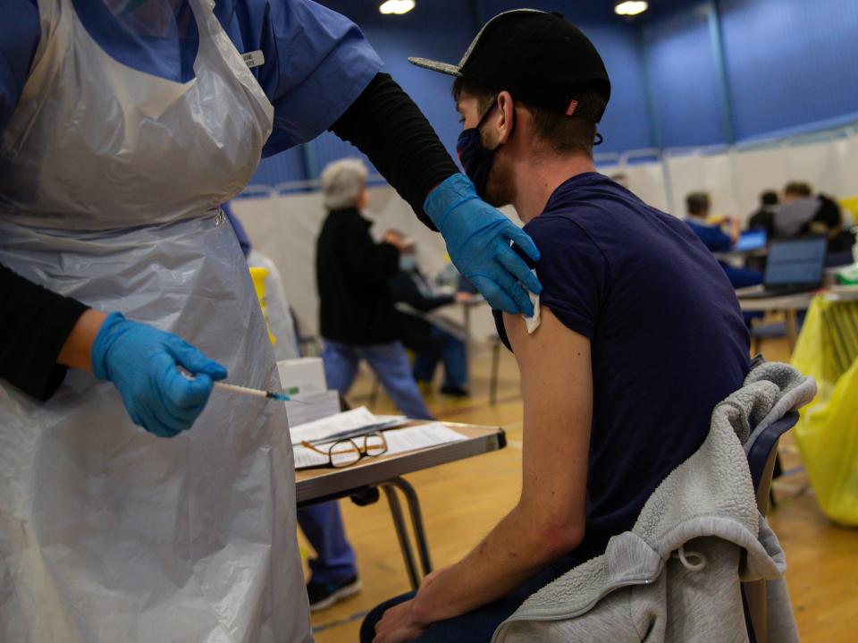 CWMBRAN, WALES - DECEMBER 29:  A general view of a NHS worker as he receives his first dose of the Pfizer/BioNTech vaccine in the waiting area for any adverse reactions on December 29, 2020 in Cwmbran, Wales. Various locations across United Kingdom were designated as covid-19 vaccine hubs. NHS staff, over-80s, will be among the first to receive the Pfizer/BioNTech vaccine, which recently received approval from the country's health authorities. It is anticipated that the Oxford University Vaccine will be approved within the next few days. (Photo by Huw Fairclough/Getty Images)