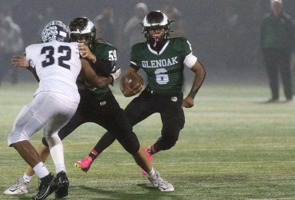 GlenOak’s Avantae Burt cuts behind the blocking of Ashton Rulewicz (59) on Lorain’s Avery Martin on Friday, Oct. 27, 2023.