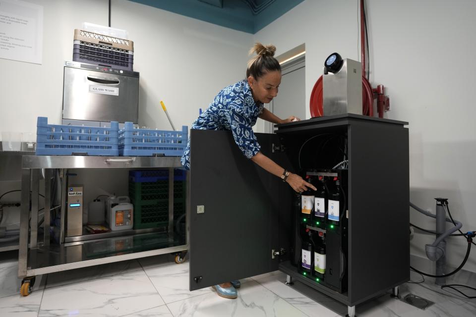 Roia Jabari, managing director of AQUA Water Bar by LUQEL works at her store in Dubai, United Arab Emirates, Tuesday, July 11, 2023. Dubai's gourmet water bar joins a growing list of unique businesses that have sprouted out of the uninterrupted stretches of windblown sand dunes turned into a bustling desert metropolis, complete with the world's tallest building, cavernous malls, and palm-shaped man-made islands. (AP Photo/Kamran Jebreili)