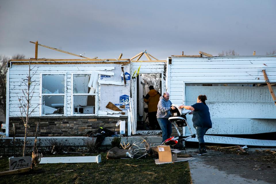 Friends help renmove person items from the tornado-damaged Dilks family home in Hills.
