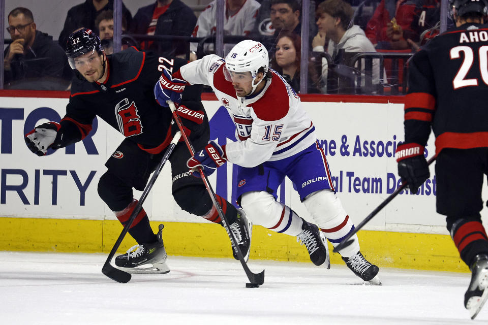 Montreal Canadiens' Alex Newhook (15) moves the puck with Carolina Hurricanes' Brett Pesce (22) nearby during the second period of an NHL hockey game in Raleigh, N.C., Thursday, March 7, 2024. (AP Photo/Karl B DeBlaker)