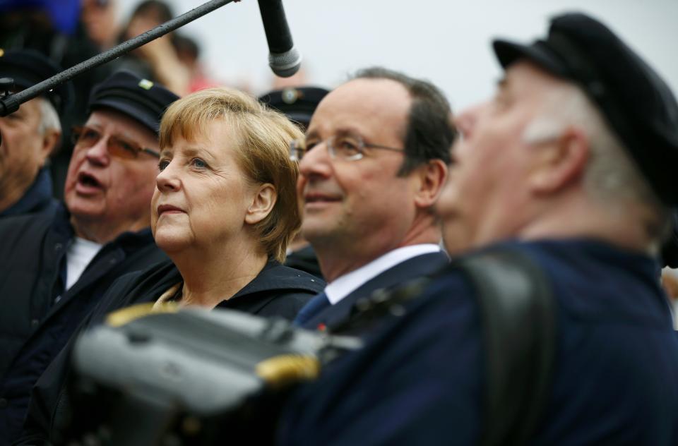 German Chancellor Angela Merkel, 2nd left, and French President Francois Hollande, 2nd right, listen to a Shanty choir before embarking on the ship Nordwind in Sassnitz on Ruegen island in the Baltic sea, Germany, Friday, May 9, 2014. (AP Photo/Thomas Peter, Pool)