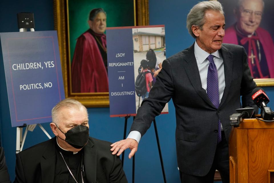 man at podium puts hand on shoulder of archbishop