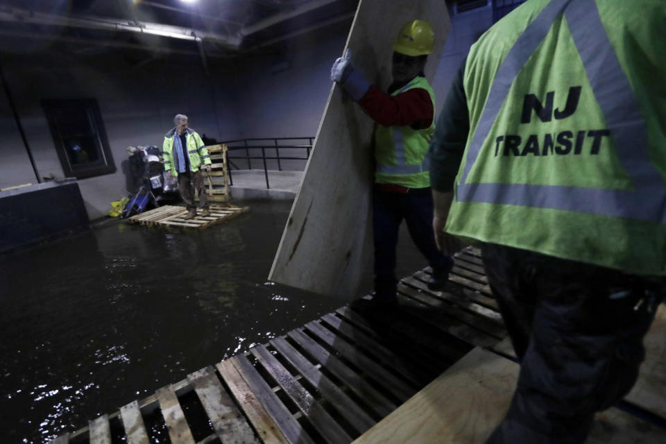 <p>New Jersey Transit workers lay down pallets and boards for commuters to walk on a flooded hallway adjacent to the site of a train crash at the Hoboken Terminal, Sept. 30, 2016, in Hoboken, N.J. Commuters are using alternative travel in and out of Hoboken a day after a commuter train crashed into the rail station, killing one person and injuring more than 100 people. (Photo: Julio Cortez/AP)</p>