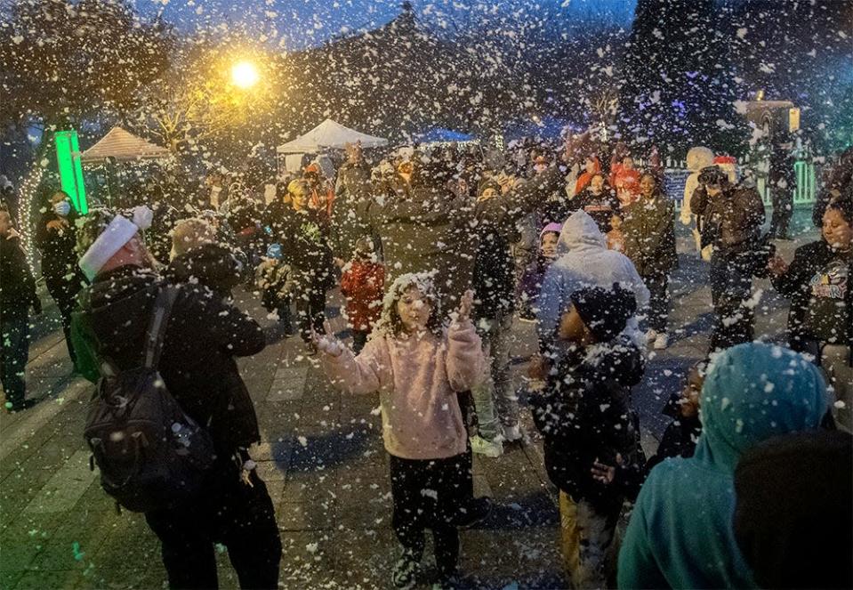 People play under a &quot;snow&quot; making machine  at the City of Stockton&#39;s annual holiday tree lighting ceremony at the Weber Point Events Center in downtown Stockton.  