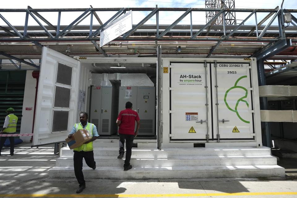 Un trabajador pasa caminando frente al sistema de almacenamiento de energía en baterías de 500 kilovatios dentro de la fábrica de Hindustan Coca-Cola Beverages en el distrito de Thiruvallur, en las afueras de Chennai, India, el martes 16 de julio de 2024. (Foto AP/Mahesh Kumar A.)