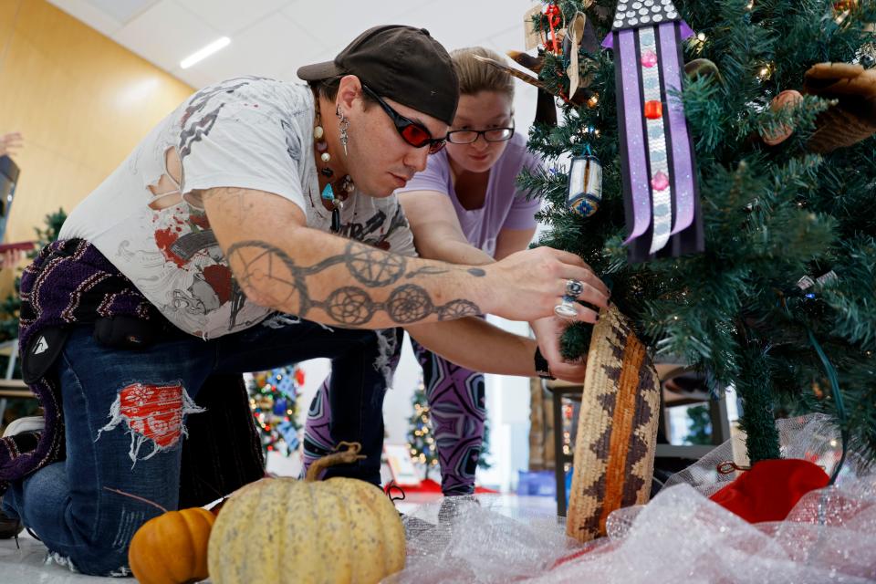 Jay Hawkins, left, and Cheyene Thom decorate the Caddo Nation tree for display before the annual Red Earth TreeFest at the Red Earth Art Center in the lobby of BancFirst Tower in Oklahoma City, Thursday, Nov. 9, 2023.