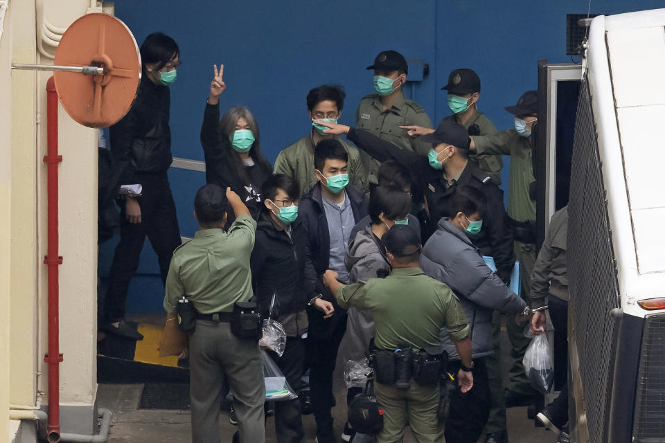FILE - Former lawmaker Leung Kwok-hung, known as "Long Hair," second from left, shows a victory sign as some of the 47 pro-democracy activists are escorted by Correctional Services officers to a prison van in Hong Kong on March 4, 2021. (AP Photo/Kin Cheung, File)