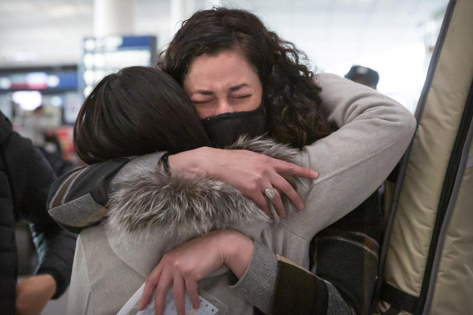 FILE - Wall Street Journal reporters Julie Wernau embraces a colleague before her departure at Beijing Capital International Airport in Beijing on March 28, 2020. China and the U.S. have agreed to ease restrictions on each other's media workers amid a slight easing of tensions between the two sides. The announcement in the official China Daily newspaper on Wednesday, Nov. 17, 2021 said the agreement was reached ahead of Tuesday's virtual summit between Chinese leader Xi Jinping and U.S. President Joe Biden. (AP Photo/Mark Schiefelbein, File)