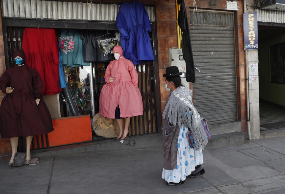 Una mujer aymara observa maniquíes en una tienda que vende ropa de protección adecuada para el estilo de vestir de las mujeres indígenas bolivianas en medio de la pandemia del nuevo coronavirus en La Paz, Bolivia, el miércoles 3 de junio de 2020. (AP Foto/Juan Karita)