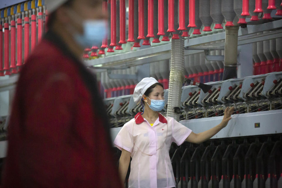 A worker checks machines processing cotton yarn at a Huafu Fashion plant, as seen during a government organized trip for foreign journalists, in Aksu in western China's Xinjiang Uyghur Autonomous Region, Tuesday, April 20, 2021. A backlash against reports of forced labor and other abuses of the largely Muslim Uyghur ethnic group in Xinjiang is taking a toll on China's cotton industry, but it's unclear if the pressure will compel the government or companies to change their ways. (AP Photo/Mark Schiefelbein)