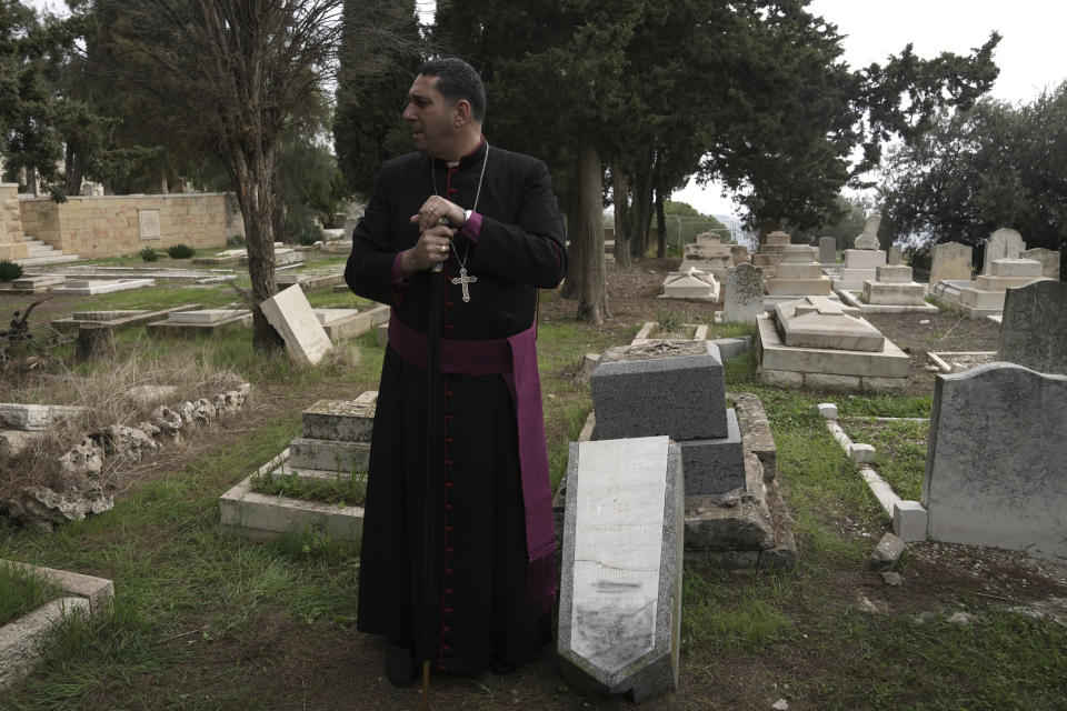 Hosam Naoum, a Palestinian Anglican bishop, pauses next to a damaged grave where vandals desecrated more than 30 graves at a historic Protestant Cemetery on Jerusalem's Mount Zion in Jerusalem, Wednesday, Jan. 4, 2023. Israel's foreign ministry called the attack an "immoral act" and "an affront to religion." Police officers were sent to investigate the profanation. (AP Photo/ Mahmoud Illean)