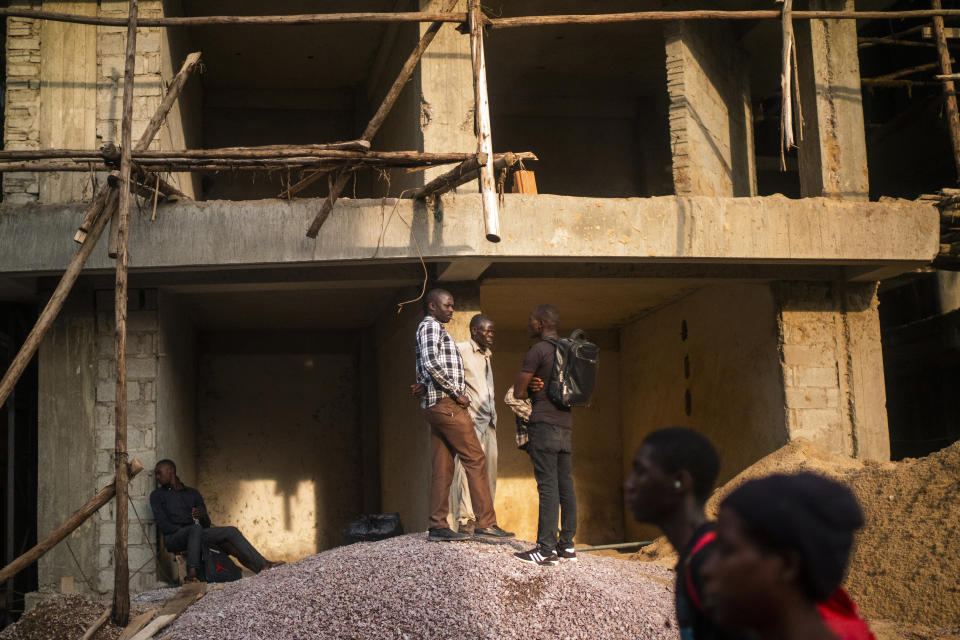 Men gather to talk on a construction site in Kampala, Uganda Wednesday, Jan. 13, 2021.The United States ambassador to Uganda said Wednesday the embassy has canceled plans to observe the country's tense presidential election on Thursday, citing a decision by electoral authorities to deny accreditation to most members of the observation team.(AP Photo/Jerome Delay)