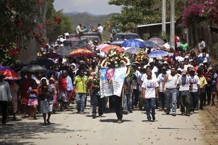 A man carries a wreath and a banner as relatives and friends of Antonio Zambrano-Montes carry his coffin toward the cemetery in Pomaro, in the Mexican state of Michoacan March 7, 2015. REUTERS/Alan Ortega