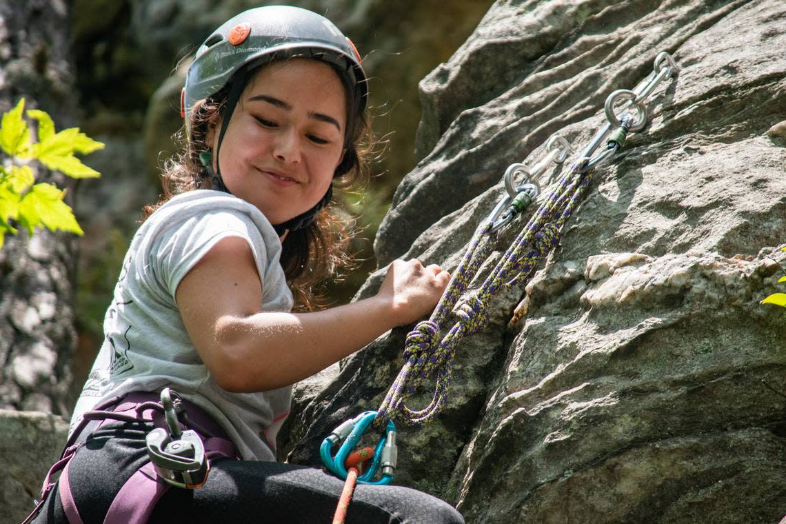 Mina Bakhshi, 20, smiles down at her friends while climbing the ‘Fear of Flying’ climbing area at Pilot Mountain State Park, north of Winston-Salem on Sunday, May 15, 2022. She is an Afghan woman living in Raleigh with a host family she met through climbing group Ascend: Leadership Through Athletics.